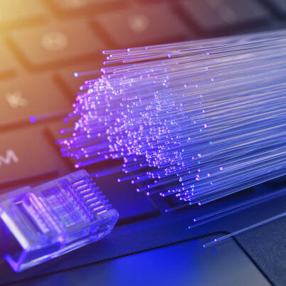 Fiber optics in blue, close up with ethernet and keyboard background, warm lens flare